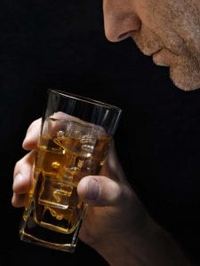 A man stares into a glass of whiskey.